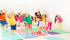 Happy kids doing side bending exercises in gym
